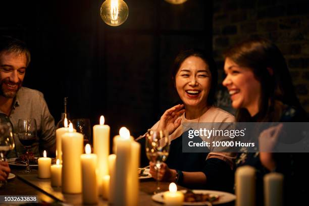 two female friends sitting next to each other and laughing during meal - reunião de amigos imagens e fotografias de stock
