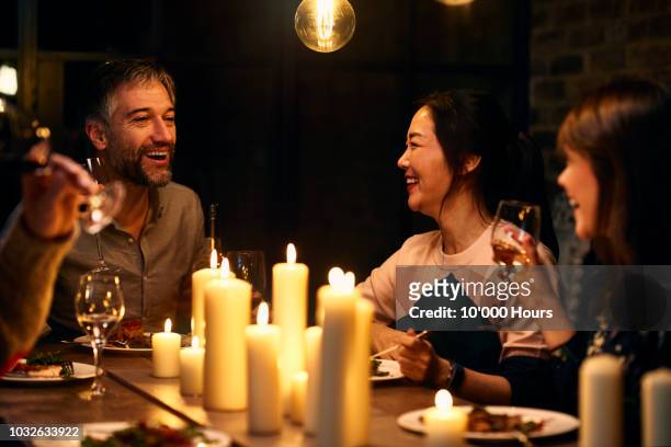 candid portrait of friends chatting over dinner with wine - evening meal restaurant stock pictures, royalty-free photos & images
