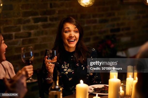 cheerful mid adult woman smiling and holding wine glass at dinner - candle light dinner stock pictures, royalty-free photos & images