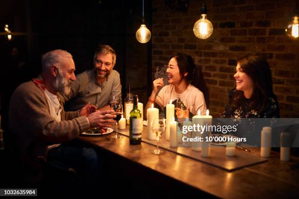 four multi racial friends sitting at dinner and having conversation - freunde restaurant stock-fotos und bilder