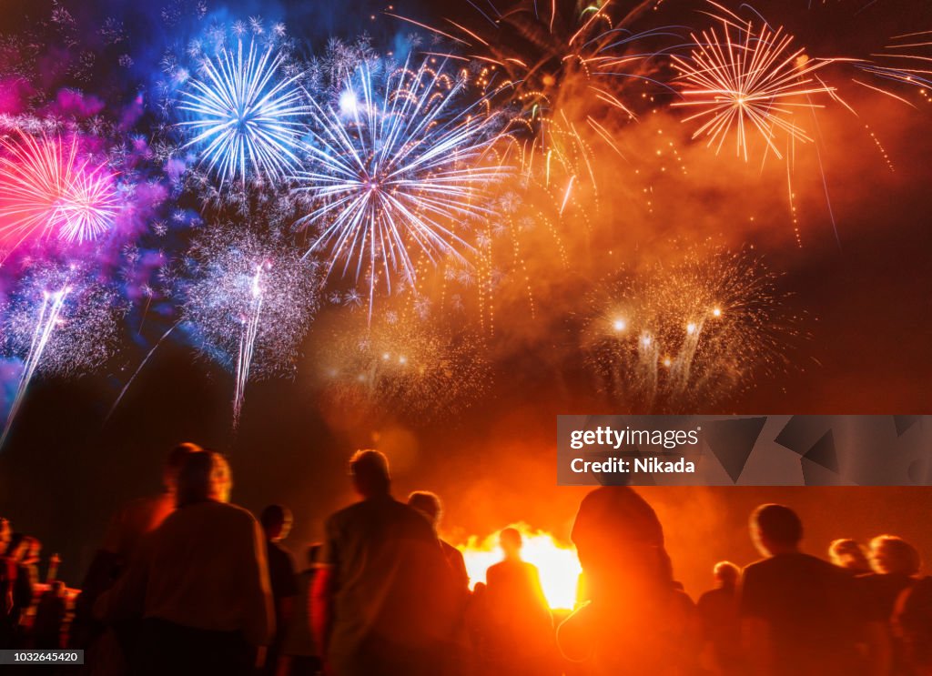 Persone in piedi di fronte a colorate opere d'artificio