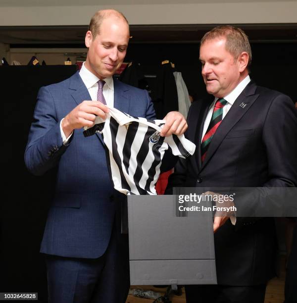 Prince William, Duke Of Cambridge is presented with a Newcastle United football shirt for his son Prince George as he attends a reception at the...