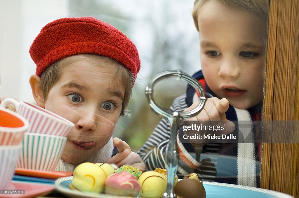 Children looking at little cakes in window display