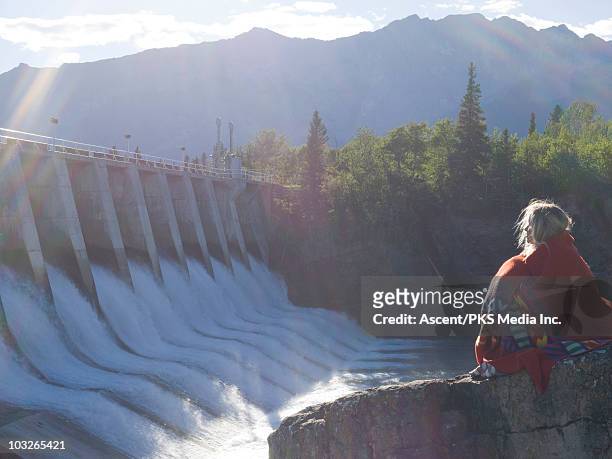 woman cloaked in blanket looks to hydro dam - hydroelectric power stock pictures, royalty-free photos & images