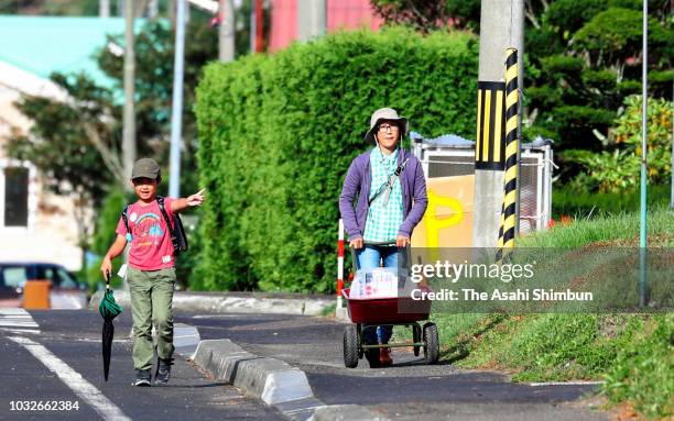 Boy walks to school with his mother, who is on the way to water distribution a week after the magnitude 6.7 earthquake on September 13, 2018 in...