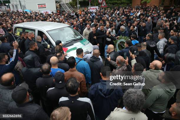 Hearse draped with a Palstinian flag arrives carrying the body of Nidal R., an associate of a Berlin Arab clan, through a crowd of mourners gathered...