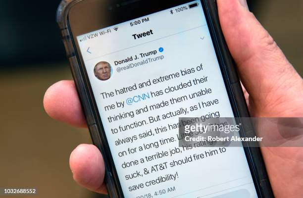 Man uses his smartphone to read a tweet from U.S. President Donald Trump attacking CNN and the television network's president, Jeff Zucker, for...