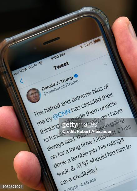 Man uses his smartphone to read a tweet from U.S. President Donald Trump attacking CNN and the television network's president, Jeff Zucker, for...