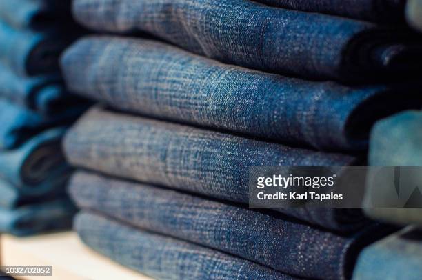 organized blue denim pants on a shelf - placard fotografías e imágenes de stock