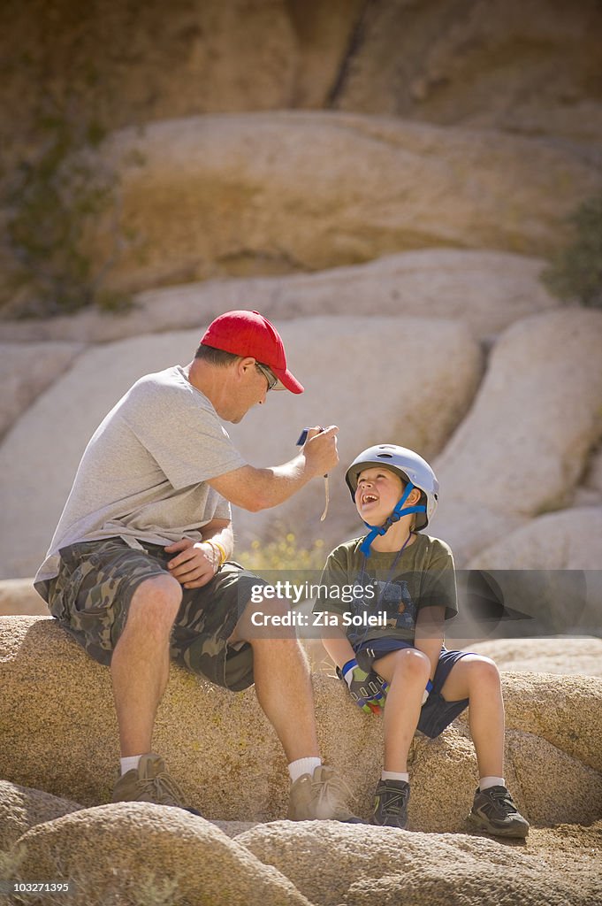 Father photographing smiling son outdoors