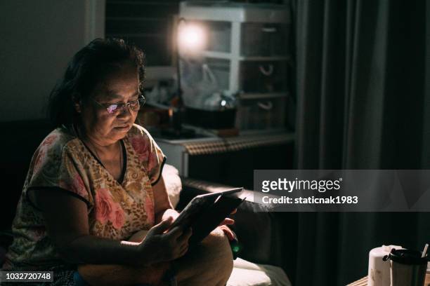 Asian senior woman sitting on the sofa and looking at photo.