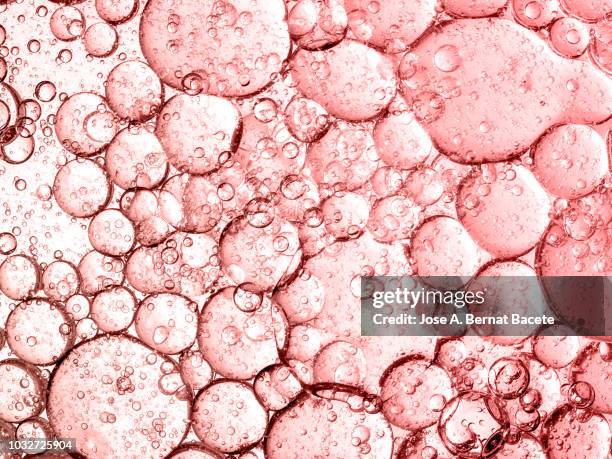 full frame of abstract shapes and textures, formed of bubbles and drops on a soft red liquid background. - brasses photos et images de collection