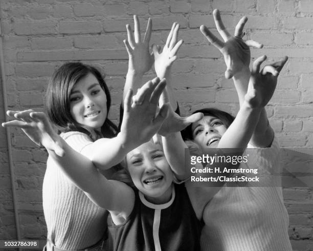 1960s THREE FRENZIED TEENAGE GIRL FANS REACHING OUT AND UP IN ADORATION LOOKING AT CAMERA