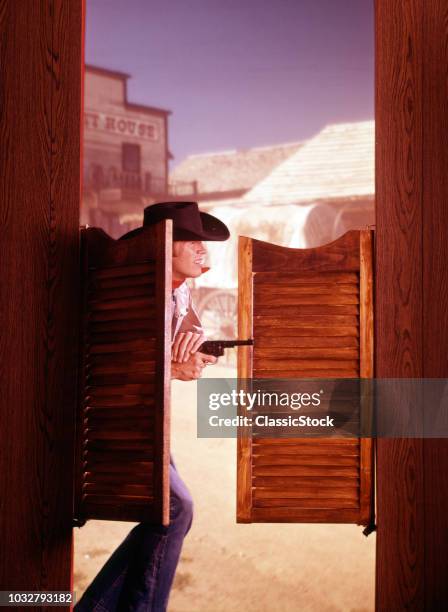 1960s 1970s WESTERN COWBOY WITH PISTOL GUN COMING THROUGH SWINGING SALOON DOORS