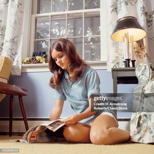 1970s TEENAGE GIRL SITTING ON FLOOR READING LIFE MAGAZINE