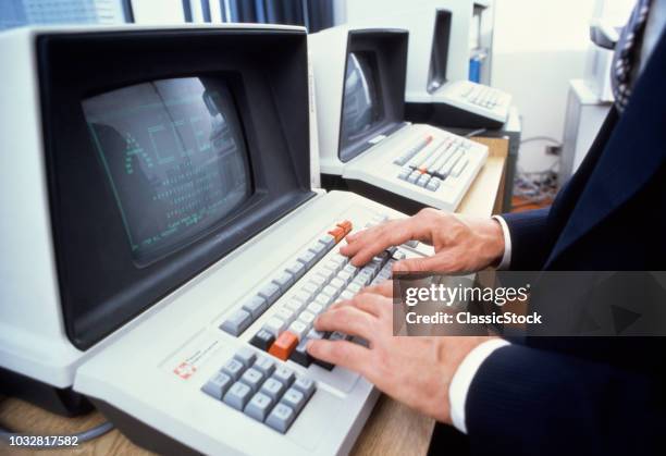 1980s MALE HANDS ON KEYBOARD OF OLD TEXAS INSTRUMENTS ANTIQUE COMPUTER TERMINAL