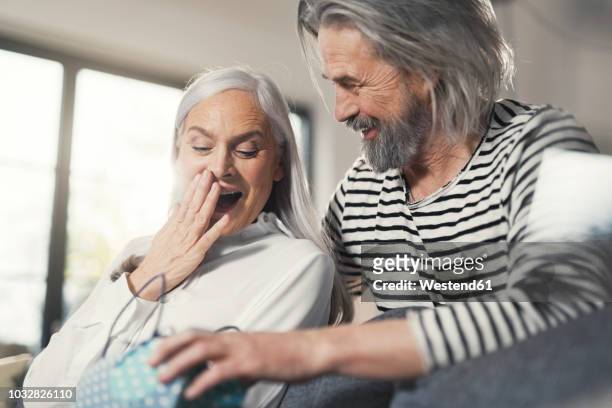 senior man surprising wife with a gift - gift lounge stock-fotos und bilder