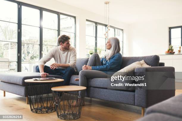 son sitting on couch, talking to his mother - erwachsene kinder stock-fotos und bilder