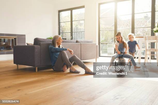grandparents observing grandmother, playing in livingroom - boy sitting on floor stockfoto's en -beelden