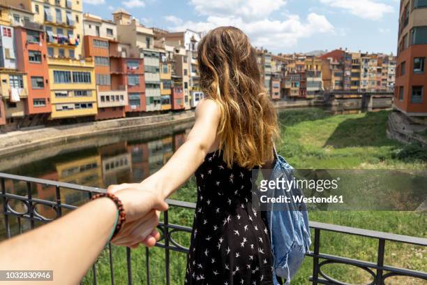 spain, girona, woman holding man's hand exploring in the city - seguir actividad móvil general fotografías e imágenes de stock