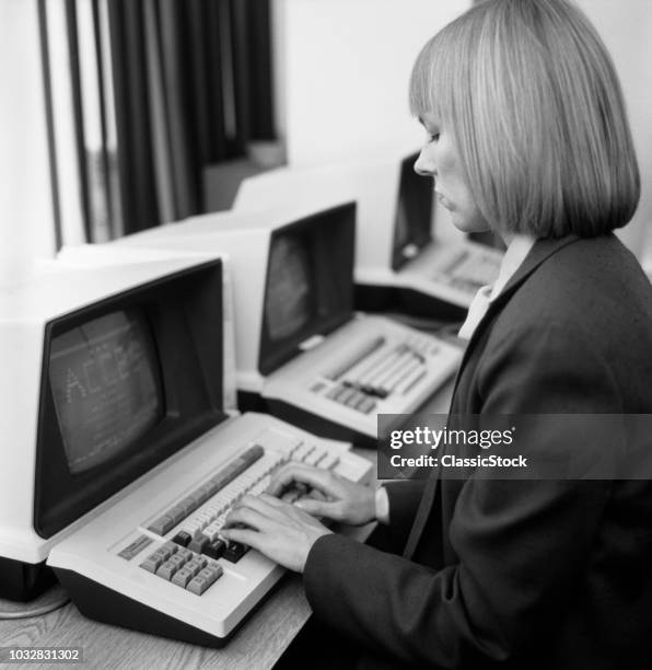 1980s WOMAN IN OFFICE AT KEYBOARD FROM BEHIND