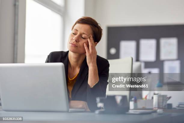 businesswoman sitting in office, having a headache - frau stress stock-fotos und bilder