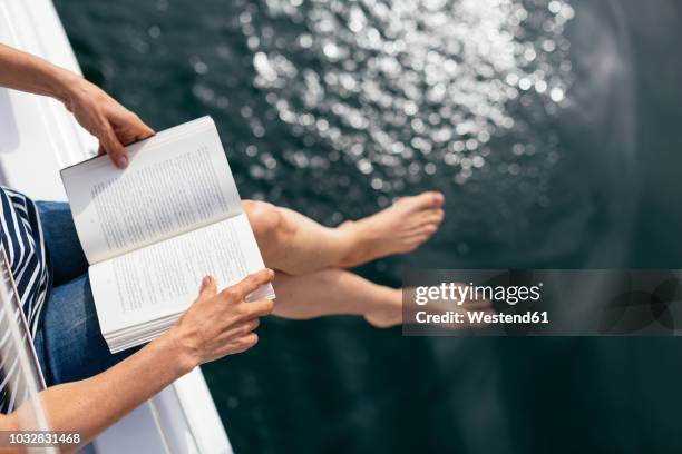 woman sitting on sailing boat, reading a book - women with nice legs stock-fotos und bilder