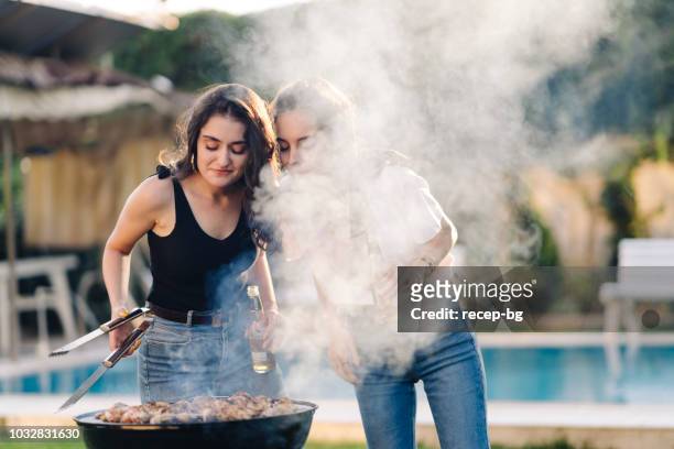 two female friends enjoying bbq party - woman laugh cook stock pictures, royalty-free photos & images