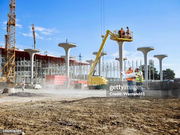 workers on construction site looking at blueprint with the architect - baustelle stock-fotos und bilder