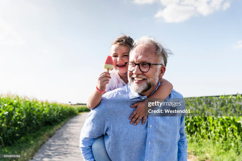 Grandfather carrying granddaughter piggyback