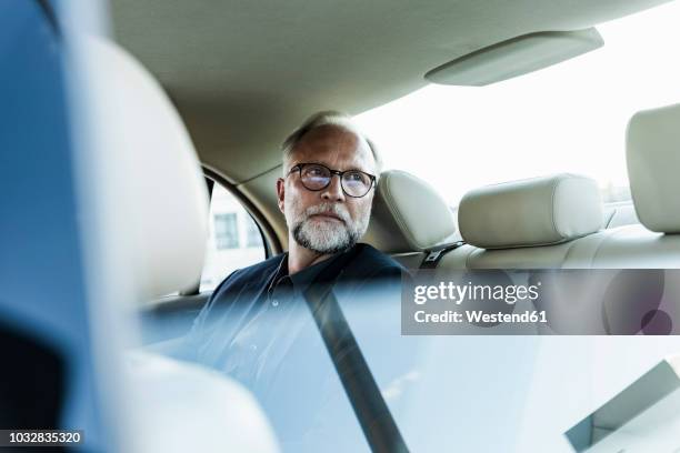 mature businessman sitting on backseat in car, looking out of window - can't decide where to go stock pictures, royalty-free photos & images