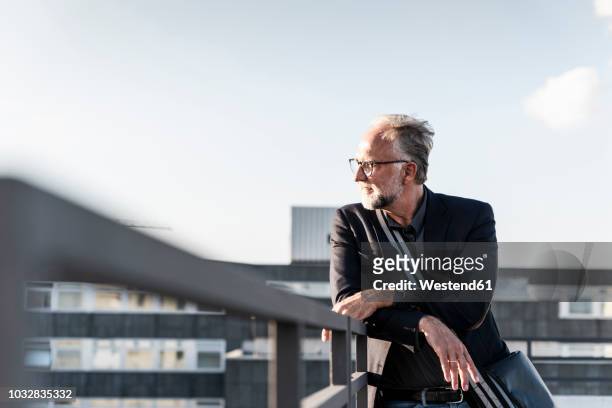 mature man standing on rooftop, leaning on railing - responsibility stock-fotos und bilder