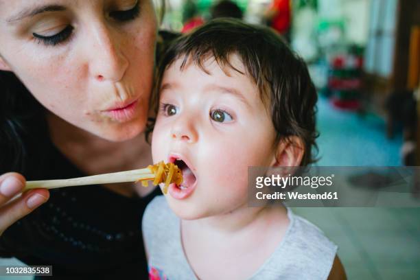 thailand, chiang mai, mother feeding her daughter with pad thai, using chopsticks - noodles eating stock pictures, royalty-free photos & images