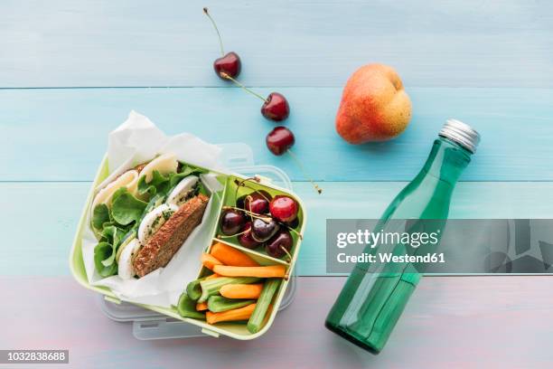 healthy school food in a lunch box, vegetarian sandwich with cheese, lettuce, cucumber, egg and cress, sliced carrot and celery, cherries and pear - lunchbox stockfoto's en -beelden