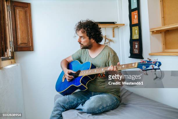 spain, man playing bass guitar in his room - bass player bildbanksfoton och bilder