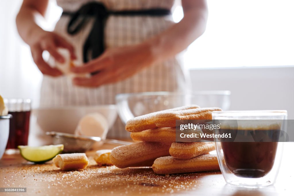 Glass of fresh coffee and heap of ladyfingers lying on table for preparing Tiramisu