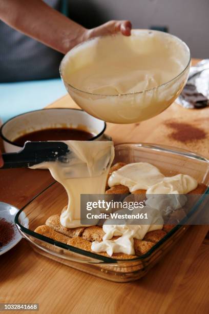 woman's hand spreading mascarpone cream on soaked ladyfingers - tiramisu stock pictures, royalty-free photos & images