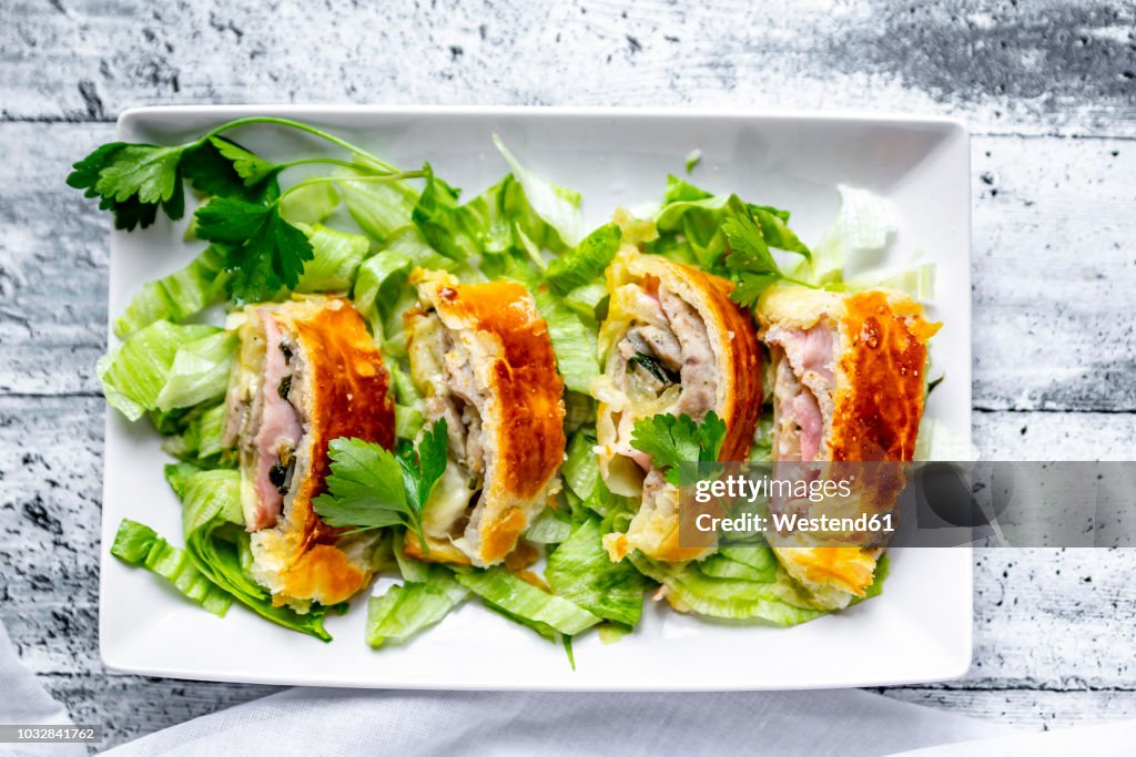 Swiss roll, puff pastry with sausage meat, cheese, onion, parsley and salad on plate