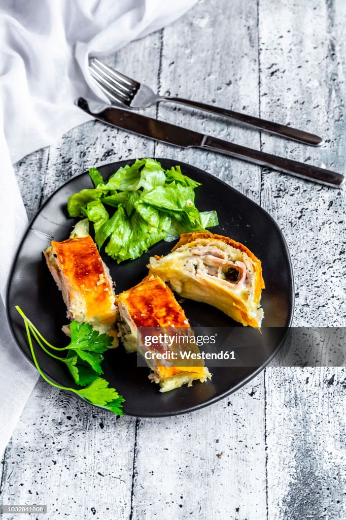 Swiss roll, puff pastry with sausage meat, cheese, onion, parsley and salad on plate