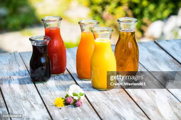 glass bottles of various fruit juices - vruchtensap stockfoto's en -beelden