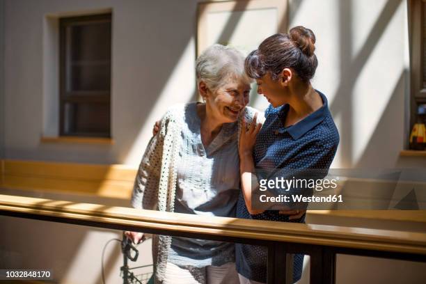 nurse embracing senior woman in retirement home - assistenza foto e immagini stock