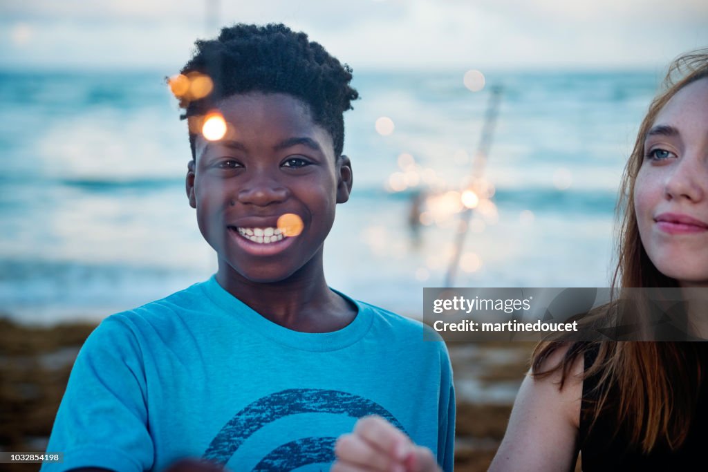 若い女性と夕暮れ時のビーチで花火をプレティーンの少年