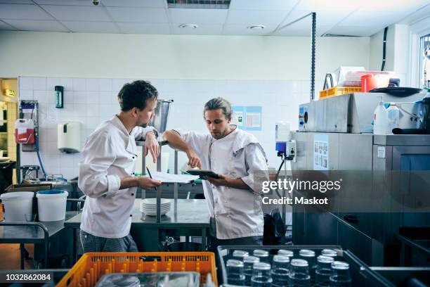 male chefs with digital tablet and documents in kitchen - restaurant cleaning stock pictures, royalty-free photos & images