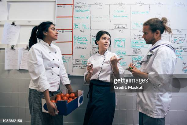 chefs communicating against whiteboard in kitchen - kochlehrling stock-fotos und bilder