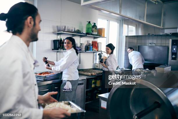 happy chefs looking at colleague in commercial kitchen - malen stockfoto's en -beelden