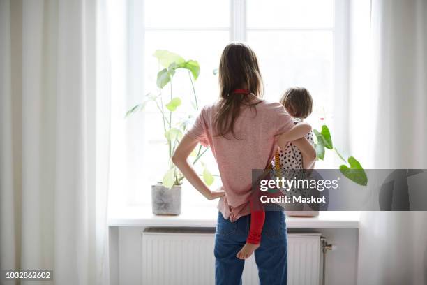 rear view of fashion designer carrying daughter while standing at home - mère célibataire photos et images de collection