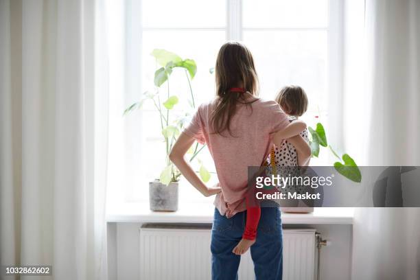 rear view of fashion designer carrying daughter while standing at home - child working stockfoto's en -beelden