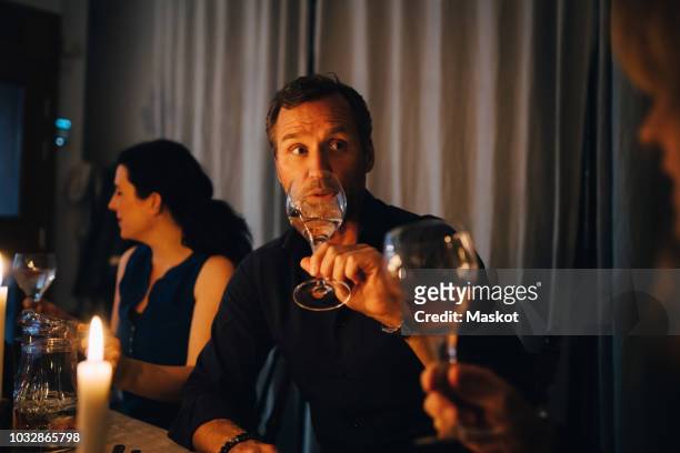 man drinking wine while sitting with female friends at dinner party - men drinking wine foto e immagini stock