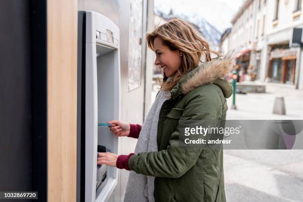 mujer feliz de poder realizar una retirada de efectivo en un cajero automático - bank holiday fotografías e imágenes de stock