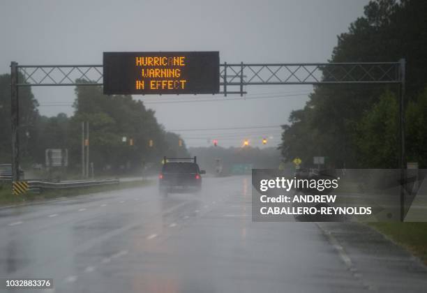 Cars drive on a wet road as rain from Hurricane Florence falls in Wilmington, North Carolina on September 13, 2018. - Hurricane Florence edged closer...